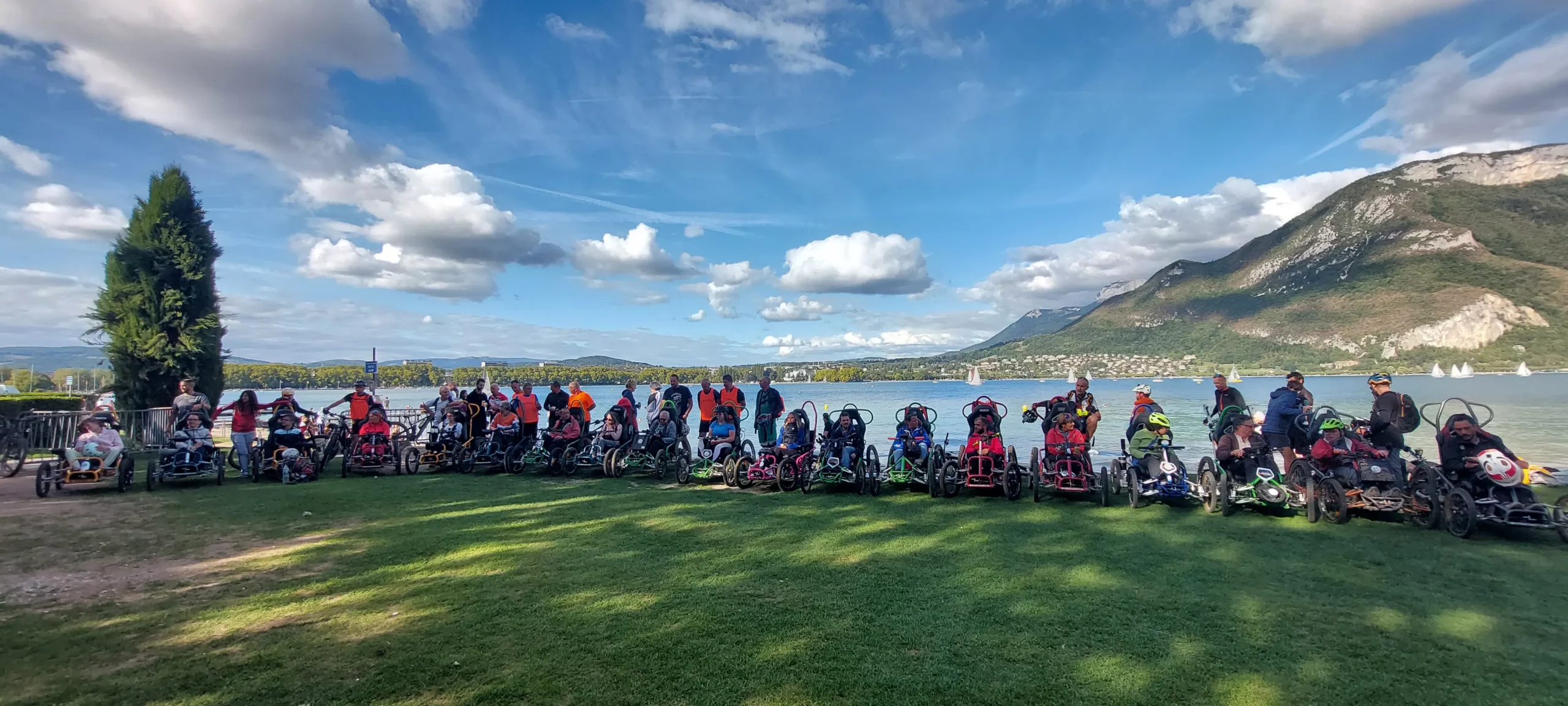 Participants du R'Handi Bike Festival qui posent devant le lac d'Annecy à la plage des Marquisats