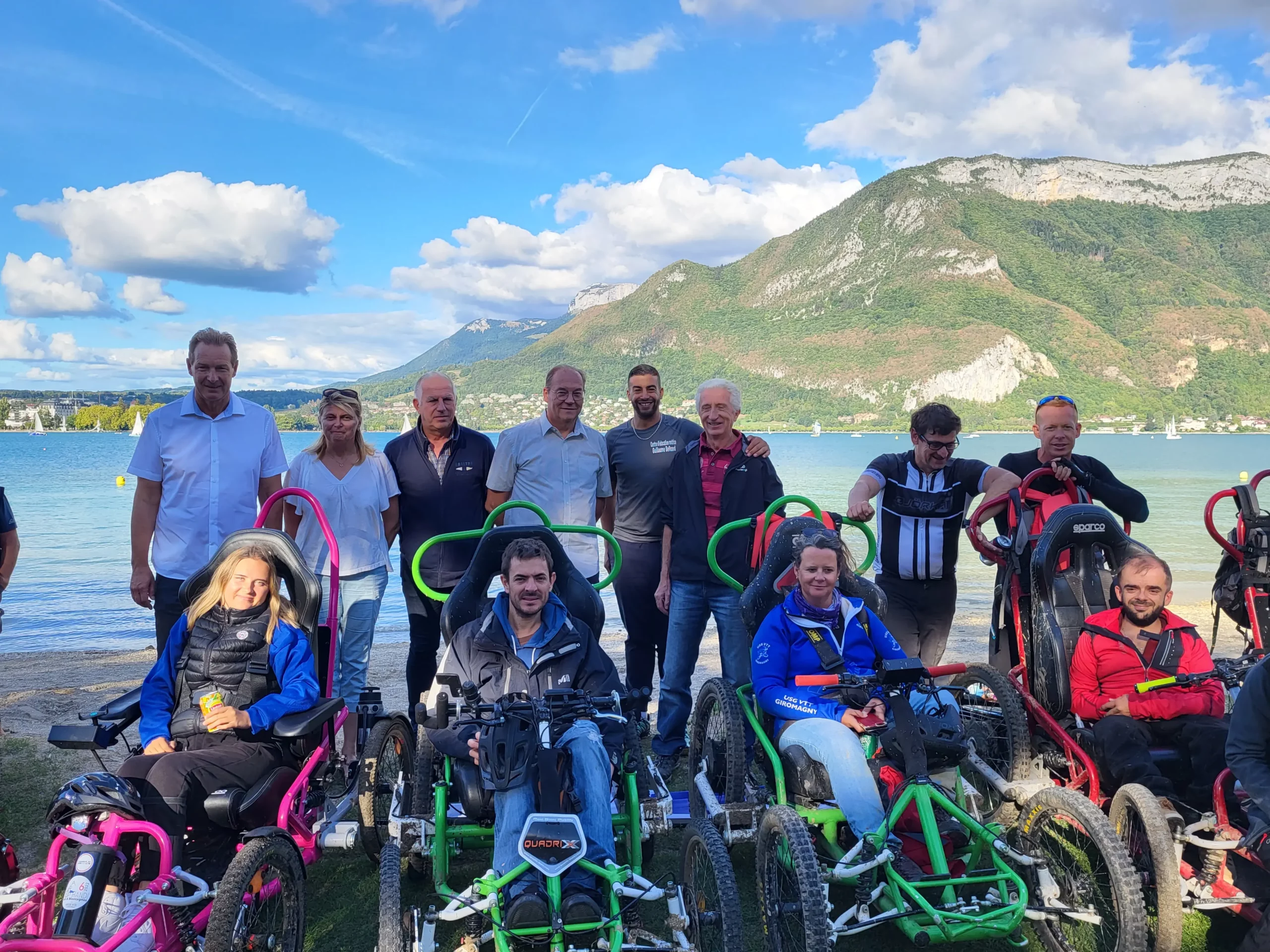 photo de participants R'Handi Bike Festival avec des élus et le président de l 'association Handi Lac & Montagnes devant le lac d'Annecy