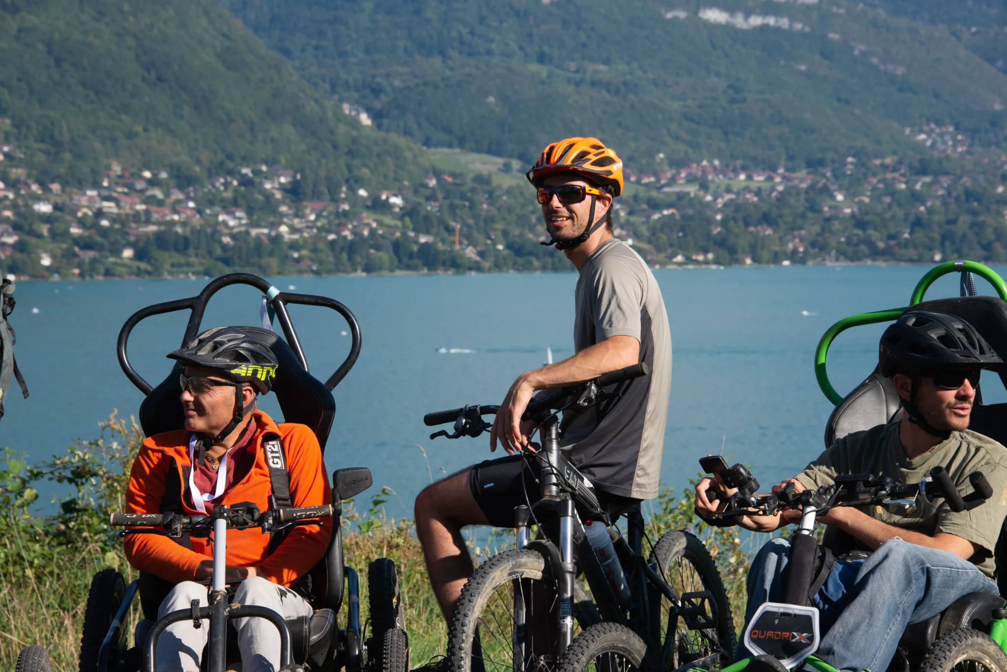Deux participants et un accompagnateur de profil devant le lac d'Annecy