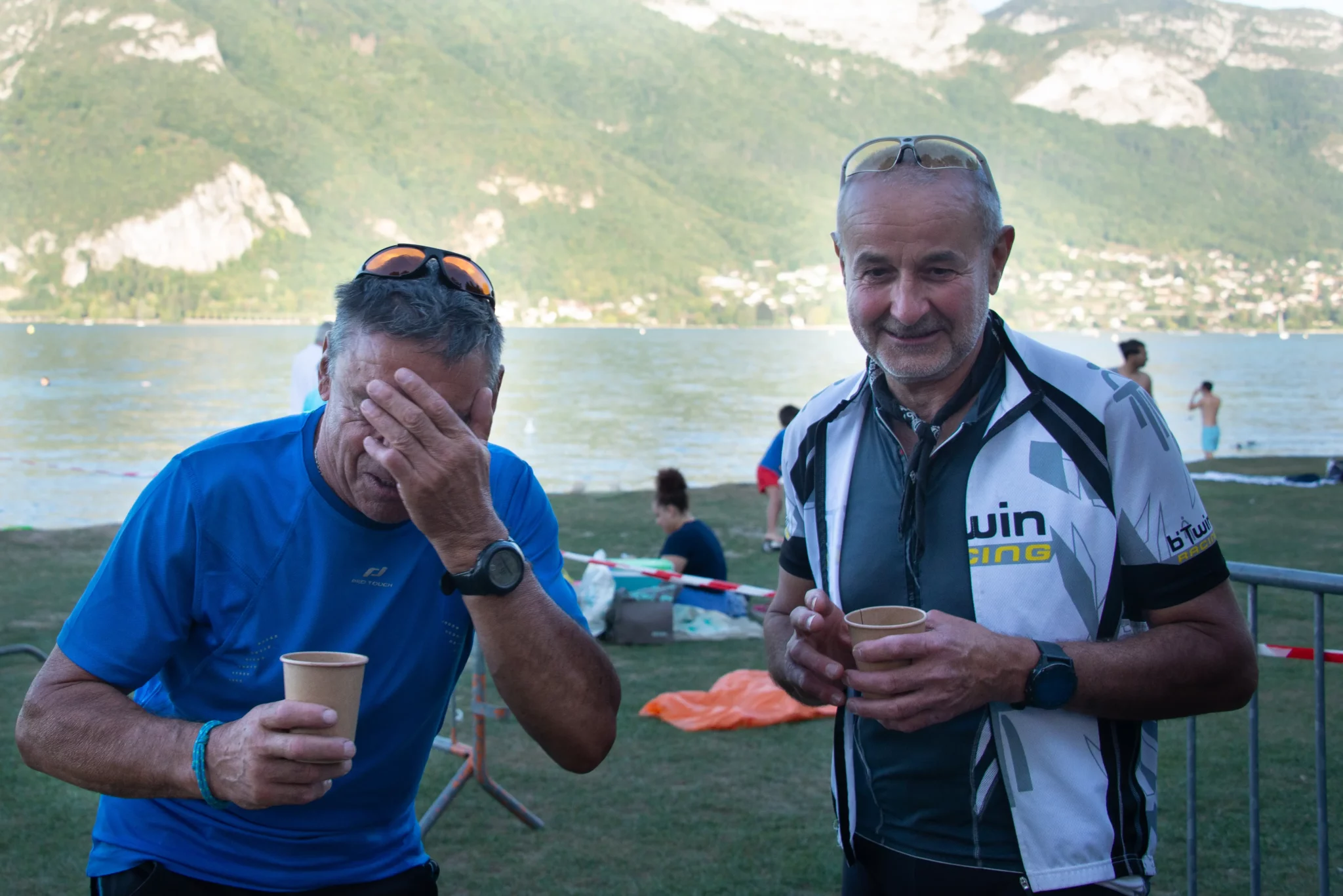Deux accompagnateurs bénévoles qui boivent un verre devant le lac d'Annecy
