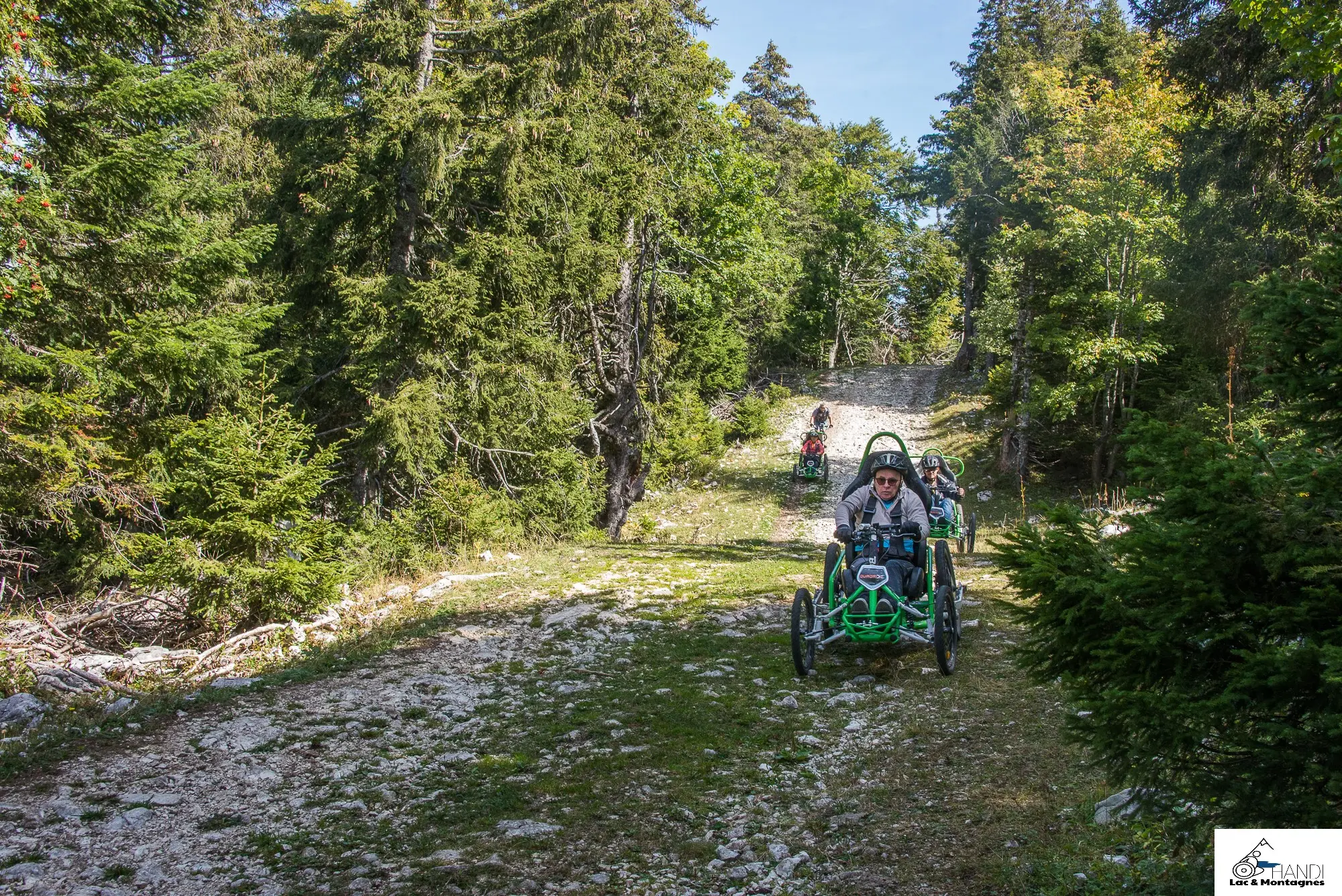 Trois participants en FTT et un accompagnateur en pleine descente dans la rocaille des pentes du Semnoz lors du R'Handi Bike Festival
