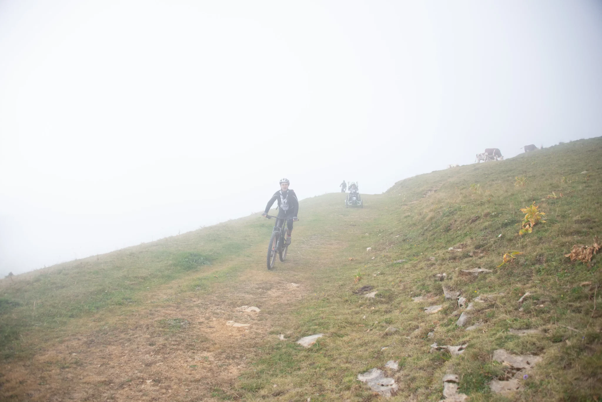 Un accompagnateur dans les nuages dans une descente sur chemin herbeux du Semnoz