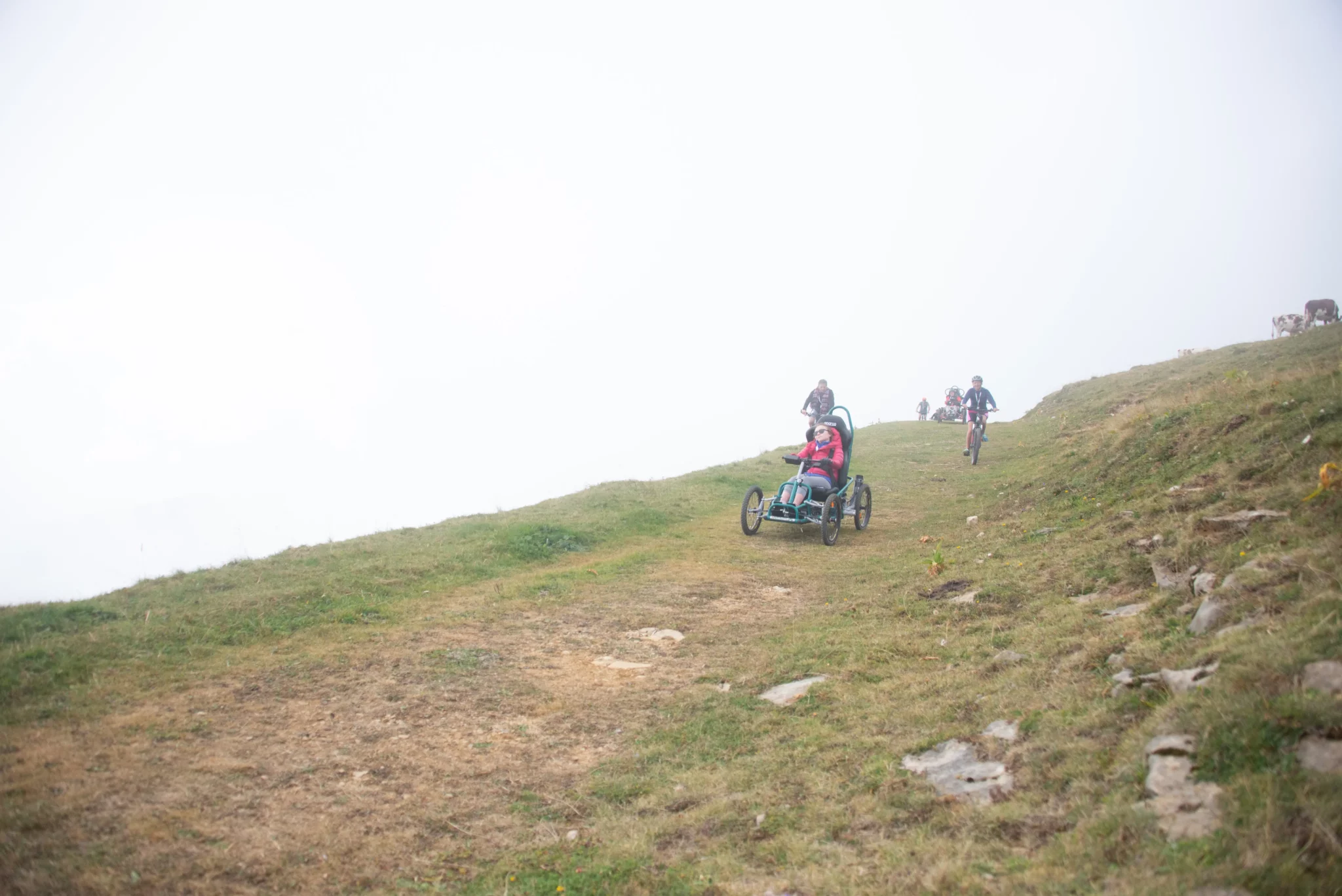 Participante en FTT et deux accompagnateurs dans une descente sur chemin herbeux du Semnoz