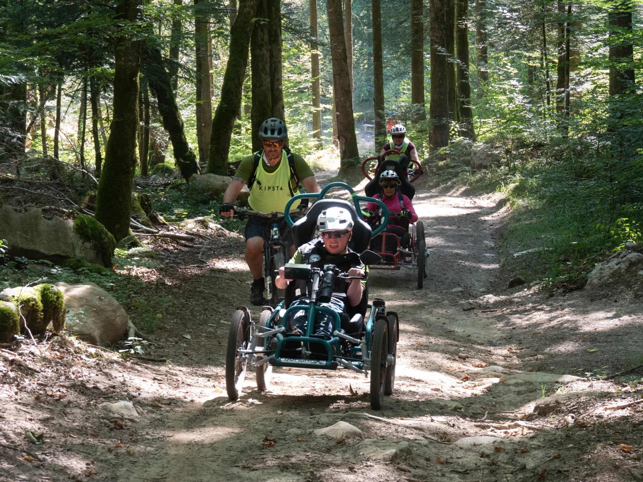 Deux accompagnateurs et deux participants dans les bois du Semnoz lors du R'Handi Bike Festival