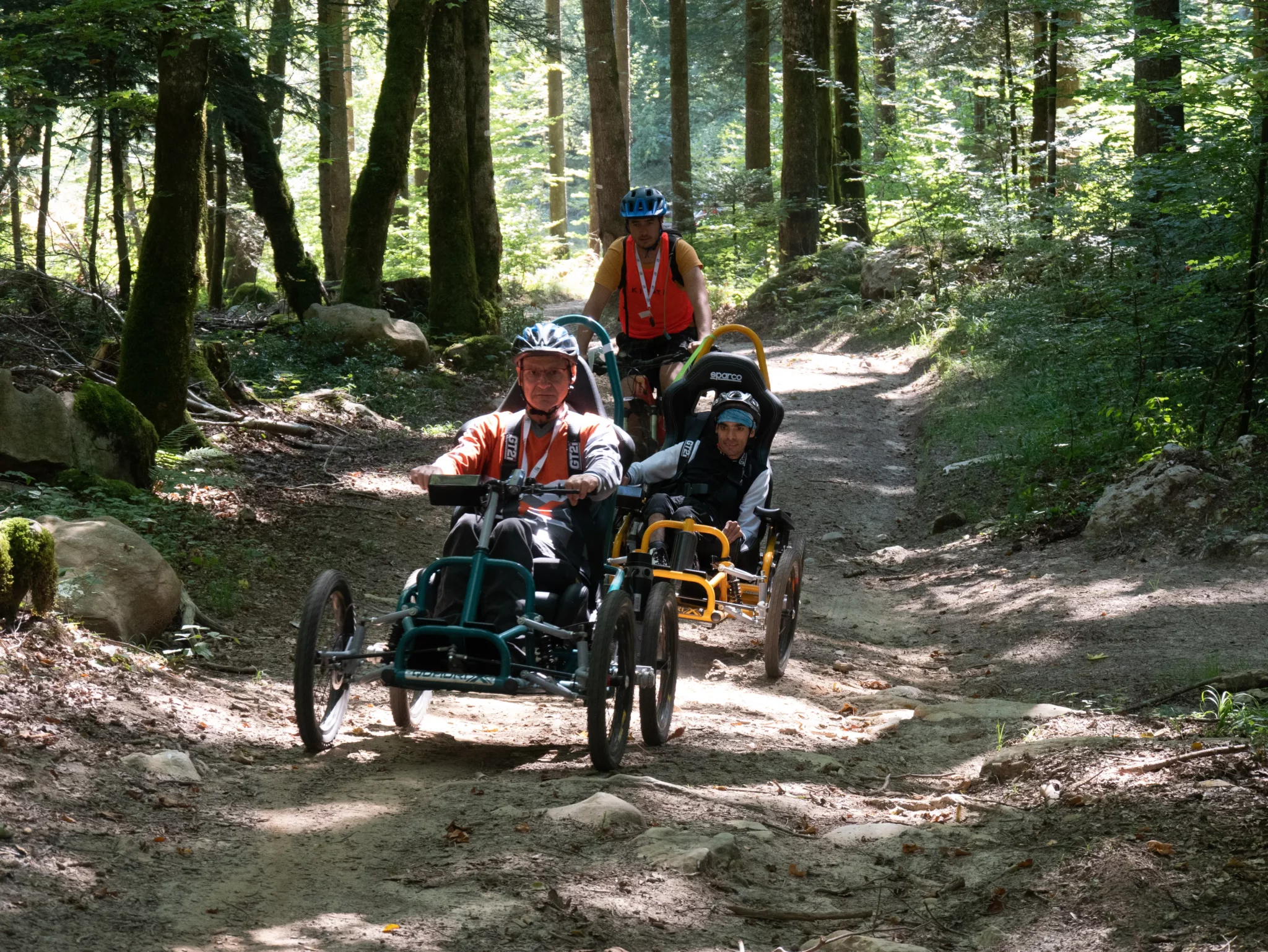 Un accompagnateur et deux participants dans les bois du Semnoz lors du R'Handi Bike Festival