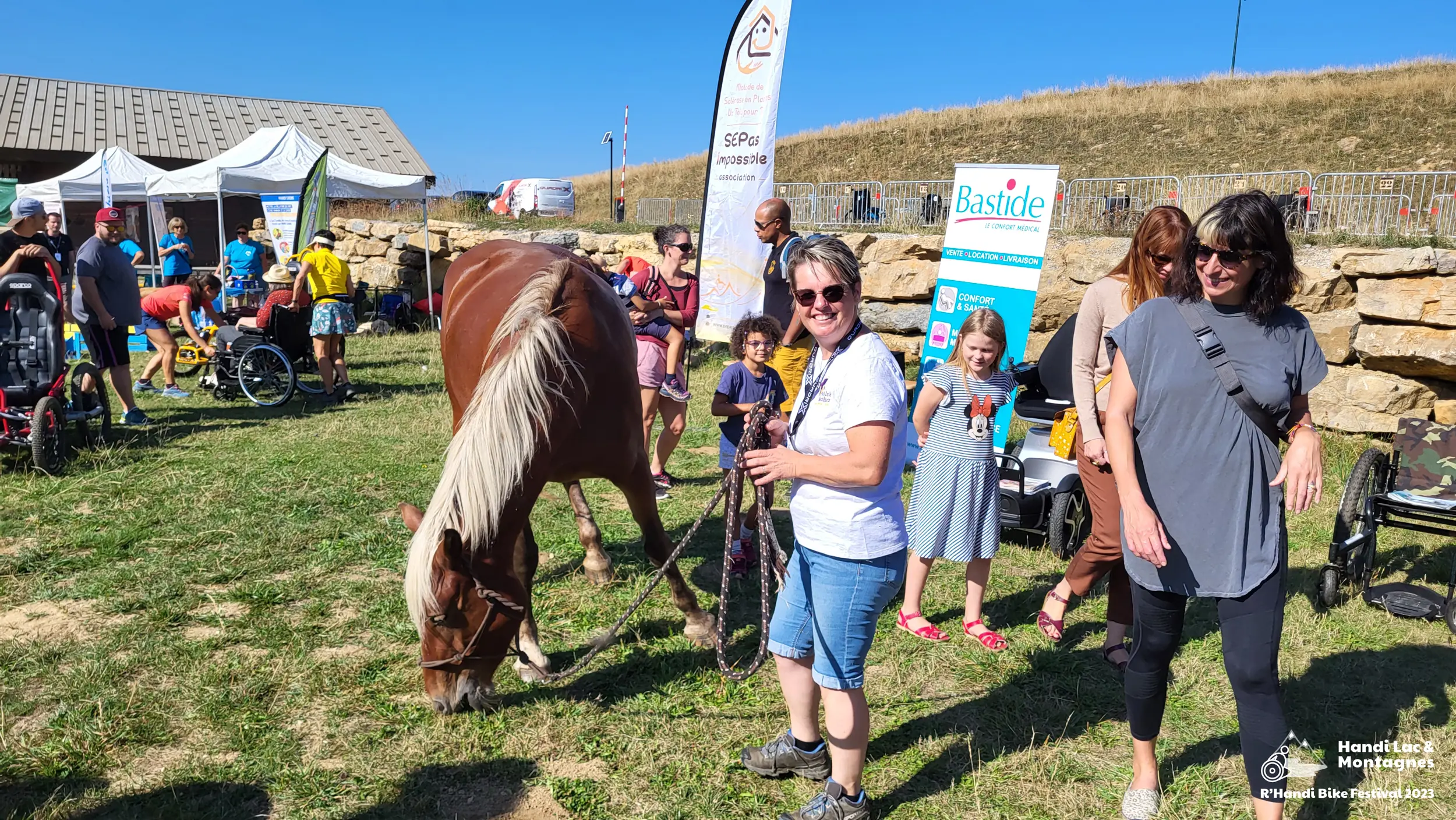 Une bénévole de Poils de Bonheur fait découvrir son cheval aux visiteurs du village du R'Handi Bike Festival 2023