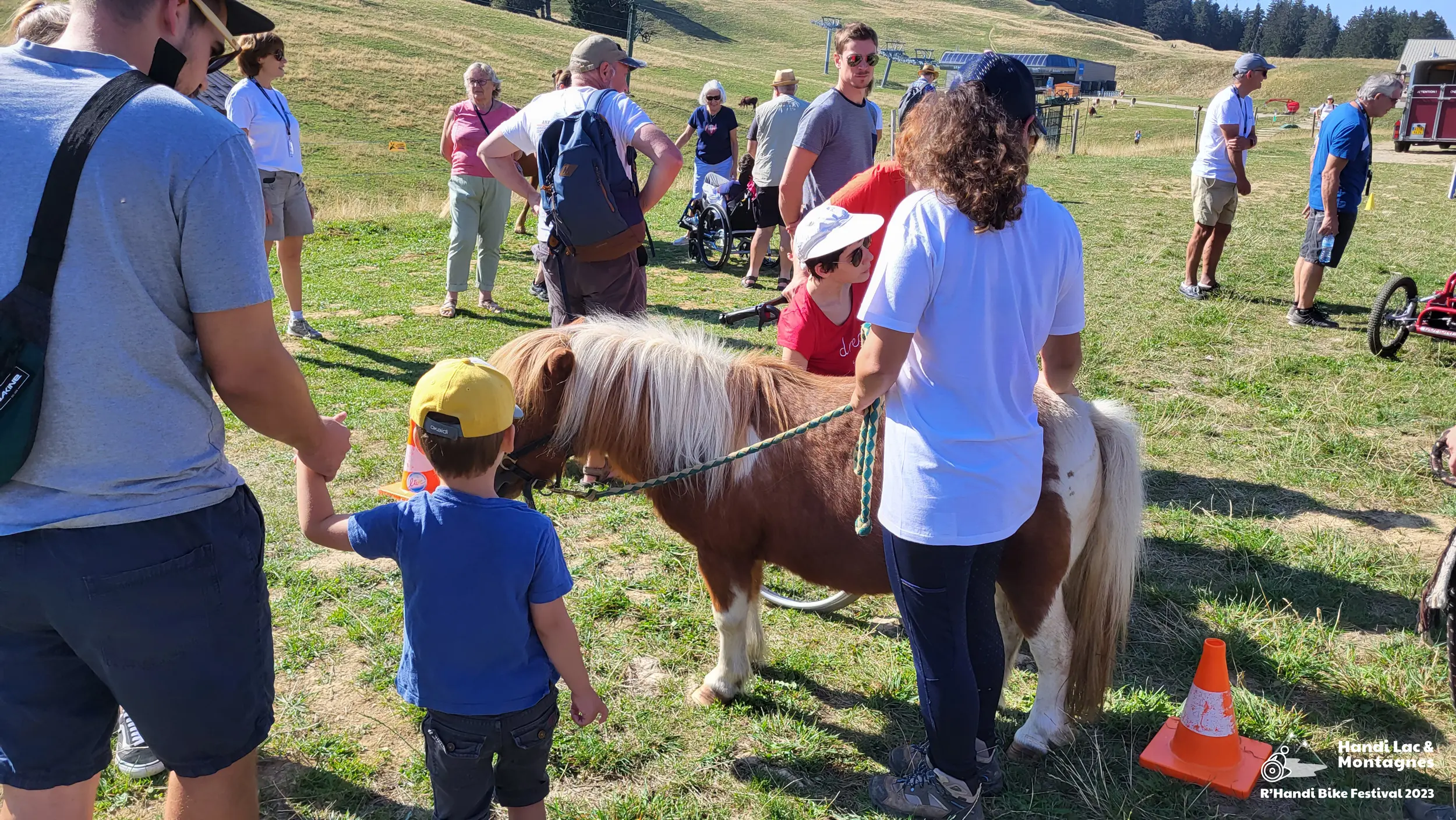 Une bénévole de Poils de Bonheur fait découvrir son poney aux visiteurs du village du R'Handi Bike Festival 2023