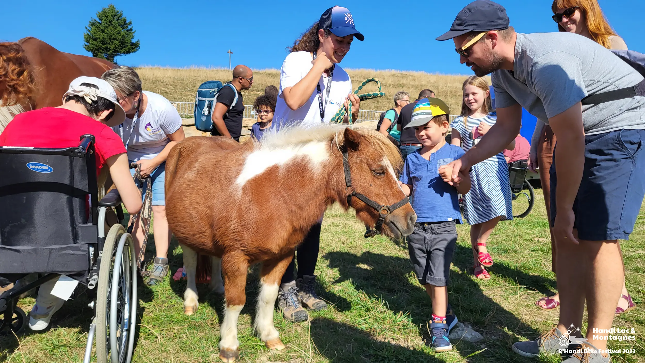 Une bénévole de Poils de Bonheur fait découvrir son poney aux visiteurs du village du R'Handi Bike Festival 2023