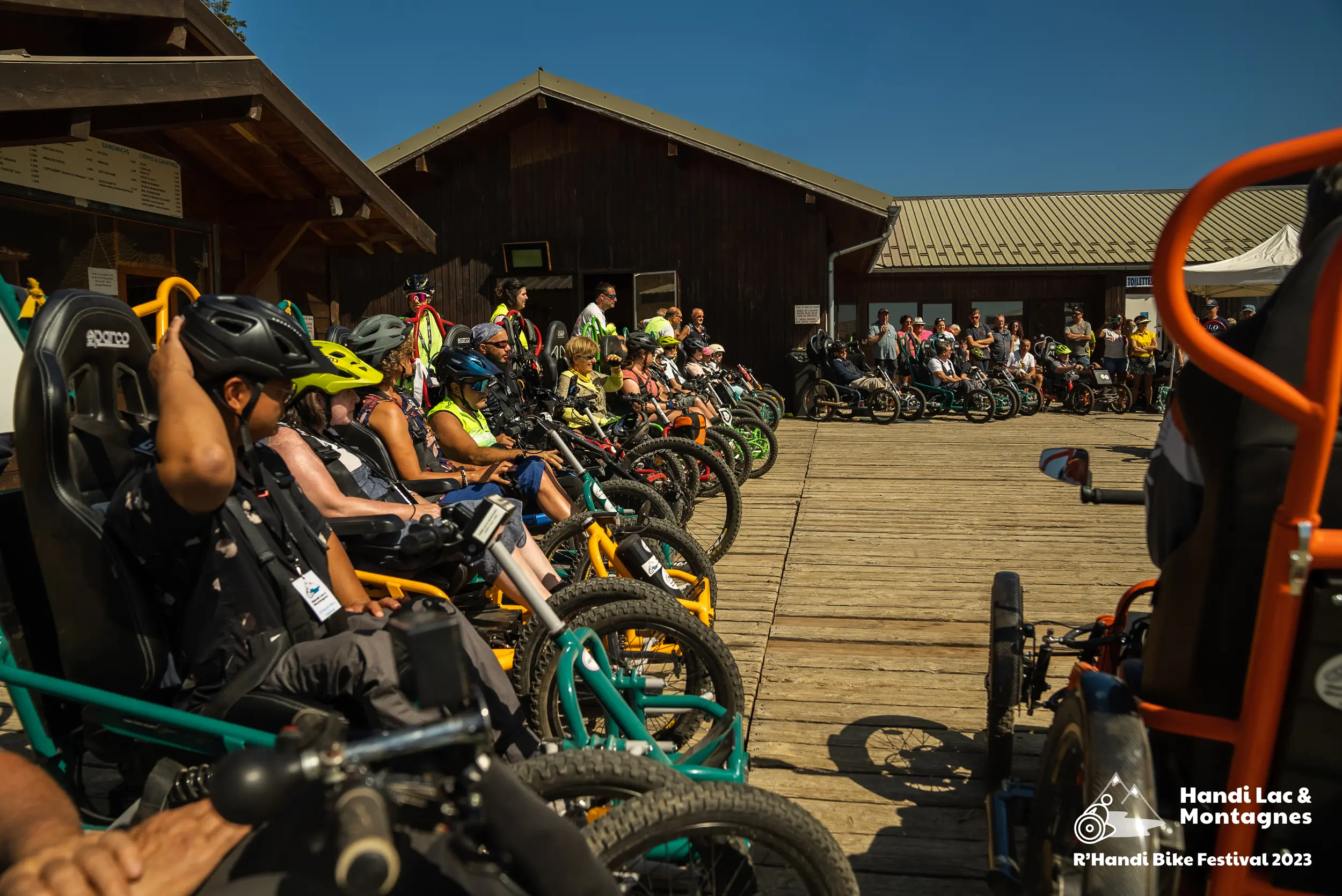 Tous les participants du R'Handi Bike Festival 2023 sont rassemblés devant les chalets au pied des pistes du Semnoz