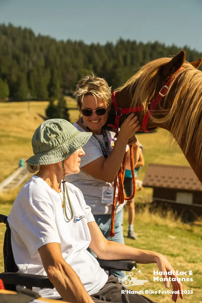 Une bénévole de Poils de Bonheur fait découvrir son cheval à une visiteuse du village du R'Handi Bike Festival 2023