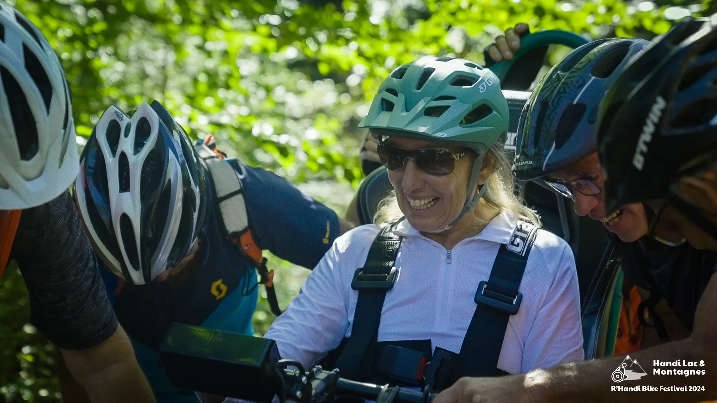 Des bénévoles aident une participante du R'Handi Bike Festival 2024 lors d'un passage difficile dans les bois du Semnoz